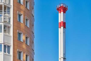 Multistorey building facade and factory chimney. photo