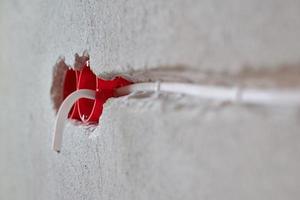 Plastic socket box and electrical wires on plastered wall photo