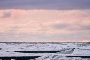 cielo nublado púrpura y mar con rompeolas de madera, paisaje marino foto