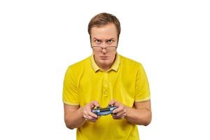 Geek gamer in glasses and yellow T-shirt with gamepad, excited video game player isolated on white photo