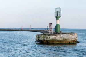 Jetty near seaport with modern lighthouse buoys. Beautiful seascape, copy space. Breakwater for protect ships at shipyard from waves photo