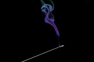 Smoke curls from burning incense stick for relaxation and meditation black background photo