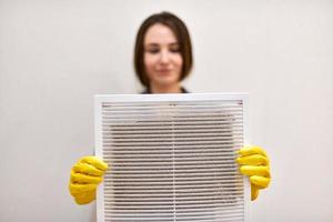 mujer sosteniendo una rejilla de ventilación sucia y polvorienta, borrosa. foto