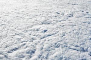 Breathtaking over clouds view from aircraft window, thick white blue clouds looks like soft foam photo