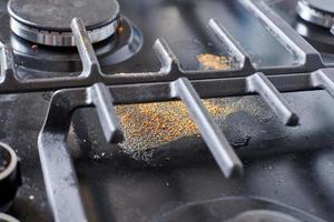 Dirty unclean kitchen black stove with dried food spots, fat stains and soup boil over leftovers photo