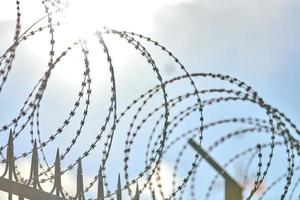 Barbed wire on fence, steel grating fence with barbs photo