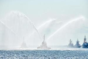 Tug boats spraying jets of water, demonstrating firefighting water cannons, fire boats spraying foam photo