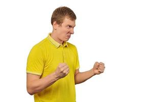 Aggressive angry man in yellow T-shirt ready to fight with fists isolated on white background photo