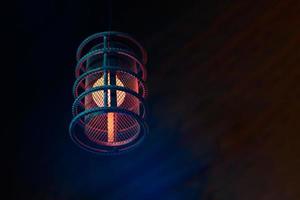 Loft pendant lamp with red blue glow in steel rebar shade, wooden interior background, copy space photo