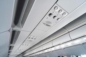 Airplane air conditioning control panel over seats. Stuffy air in aircraft cabin with people. New low-cost airline. photo