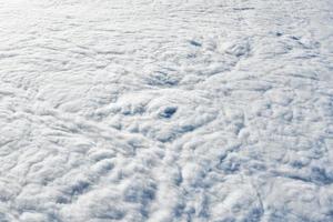 sobre la vista superior de las nubes desde la ventana del avión, las nubes azules blancas gruesas parecen espuma blanda foto