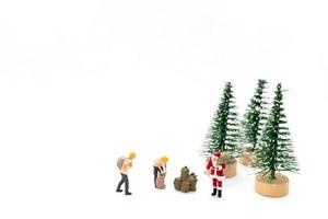 Miniature people Santa Claus carrying bag on white background photo