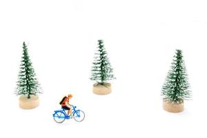 Miniature people with gifts on a bicycle on white background photo