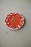 round orange wall clock with hands indicating 10 am photo