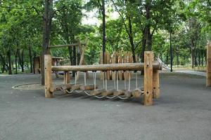 Rope bridge in outdoor modern children wooden playground in a public park of city. Eco-friendly lifestyle rest and childhood concept of safety environmentally infrastructure for kids. Funny adventure photo