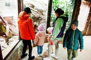 Mother with four kids discovering and watching animals at zoo. photo