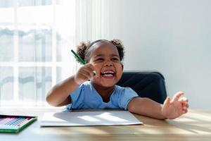 African american girl Have fun with crayons and draw on paper in the classroom. creative thinking and artistic concepts photo