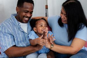 A happy African parent and two daughters sit on the sofa in the living room. Happy family concept. photo