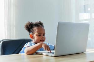 concepto educativo. pequeña y linda niña afroamericana con el pelo rizado en la sala de estudio del hogar. foto