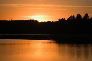 Sunset with reflection on a Swedish lake in Smalland. Romantic evening mood photo