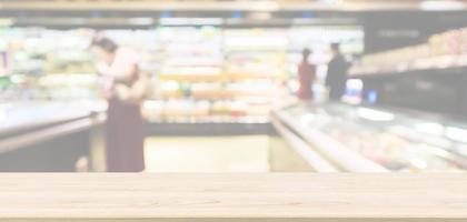 Empty wood table top with abstract supermarket aisle interior blurred defocused background with bokeh light photo