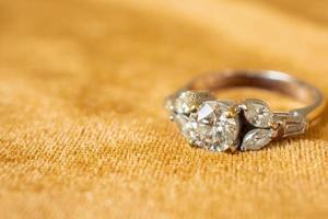 anillo de diamantes de joyería sobre fondo de tela dorada de cerca foto