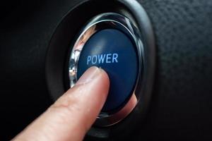 Hand push on car engine power start button close up photo