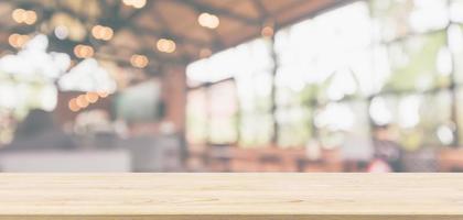 Empty wooden table top with cafe restaurant or coffee shop window interior abstract blur defocused with bokeh light background for montage product display photo