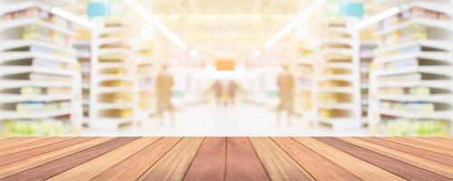 mesa de madera con fondo borroso interior del pasillo de la tienda de comestibles del supermercado con luz bokeh para la exhibición del producto foto