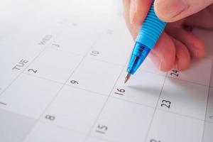 Woman hand with pen writing on calendar date business planning appointment meeting concept photo