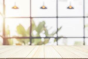Empty wooden table top with cafe restaurant coffee shop window interior abstract blur defocused with bokeh light background for montage product display photo