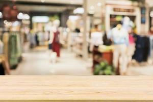 Empty wood table with woman fashionable boutique clothing store window display in shopping mall photo