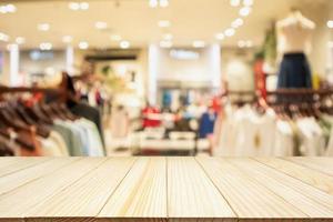 Empty wood table with woman fashionable boutique clothing store window display in shopping mall photo