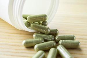 Herbal medicine capsules with bottle on wood table photo