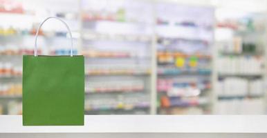 Paper bag on Pharmacy drugstore counter table with medicine and healthcare product on shelves blur background photo