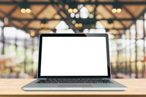 Blank white screen laptop computer on wood table top with cafe restaurant abstract bokeh light defocused blur background photo