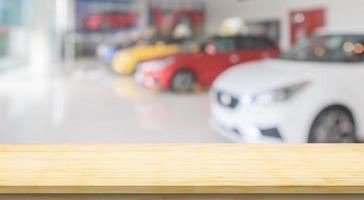 Empty wood table top with cars in showroom blurred defocused background photo
