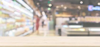 Empty wood table top with abstract supermarket aisle interior blurred defocused background with bokeh light photo
