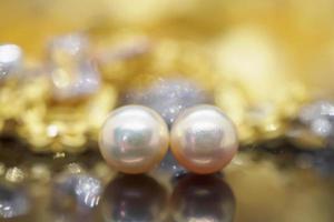 pendientes de perlas de joyería de lujo con reflejo en el fondo negro dorado foto