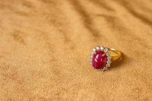 Jewelry red ruby ring on golden fabric background close up photo
