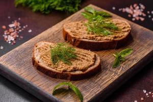 Homemade meat snack liver pate with toast on a dark concrete background photo