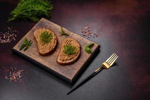 Homemade meat snack liver pate with toast on a dark concrete background photo