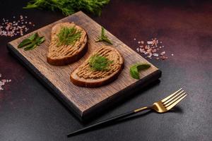 Homemade meat snack liver pate with toast on a dark concrete background photo