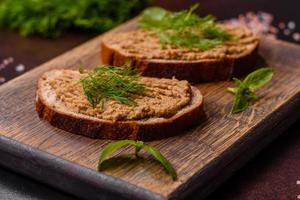 Homemade meat snack liver pate with toast on a dark concrete background photo