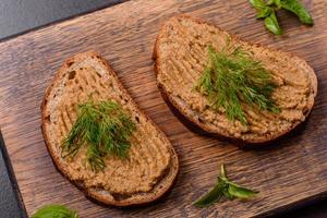 Homemade meat snack liver pate with toast on a dark concrete background photo