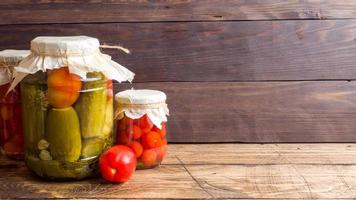 Homemade canned vegetables in cans. Pickled tomatoes and cucumbers in a rural style. Copy space photo