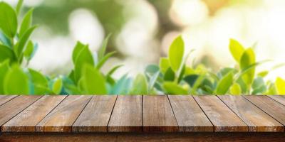Empty of wooden table top with blurry green leaf and bokeh background. For montage product display or design key visual layouts. photo