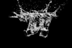 cubos de hielo en agua con burbujas sobre fondo negro foto