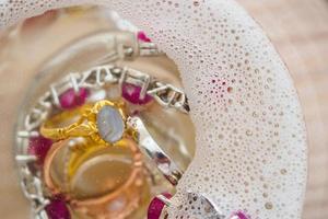 limpiar el anillo de diamantes de joyería vintage y la pulsera en vidrio sobre fondo de mesa de madera foto