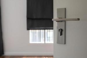 Modern door handle on white door with room interior photo